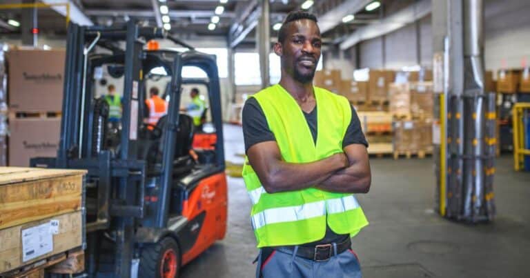 warehouse forklift driver standing next to forklift