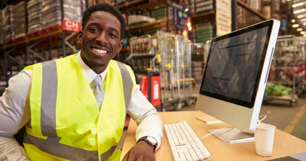 manager in warehouse in front of computer monitor