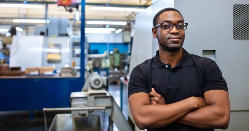 man with arms crossed on production floor