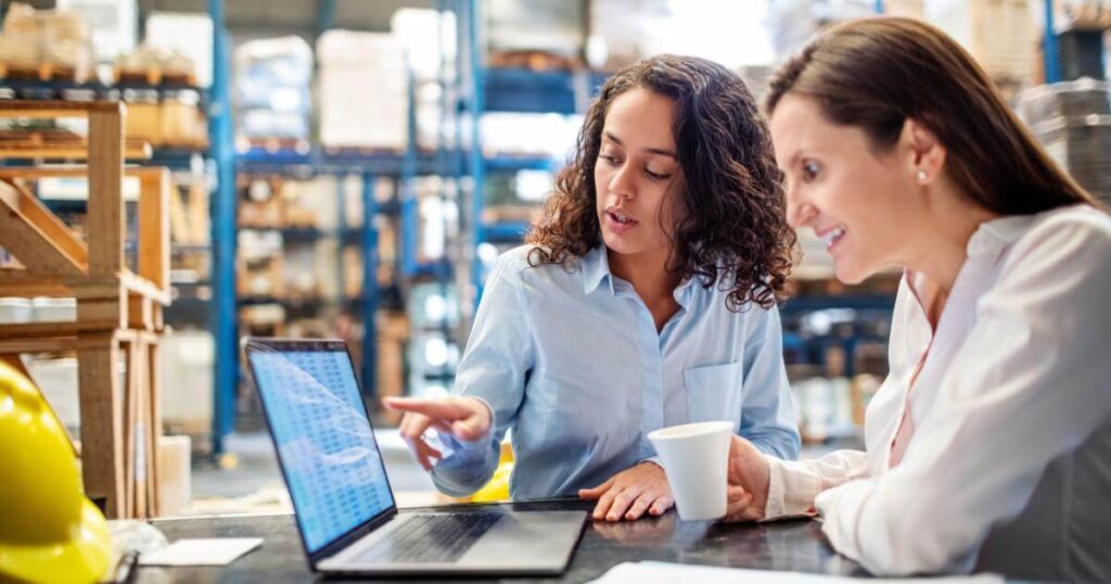 warehouse manager and staffing partner reviewing hiring data on laptop