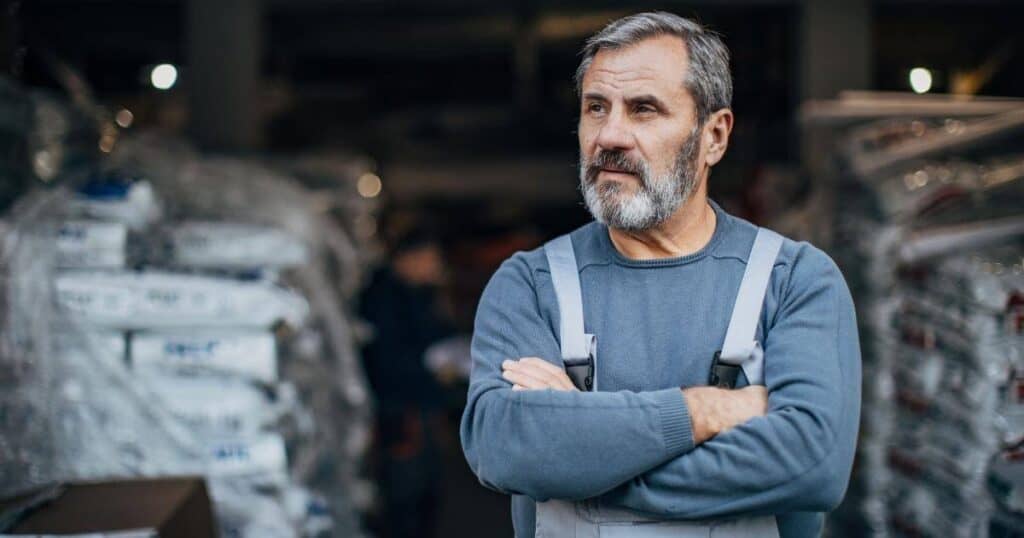 A disengaged worker stands with arms folded and looking bored