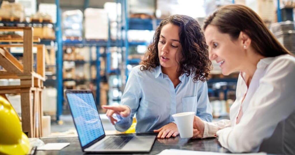 warehouse manager and staffing partner reviewing hiring data on laptop
